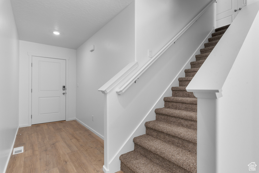 Foyer with wood finished floors, stairs, and recessed lighting