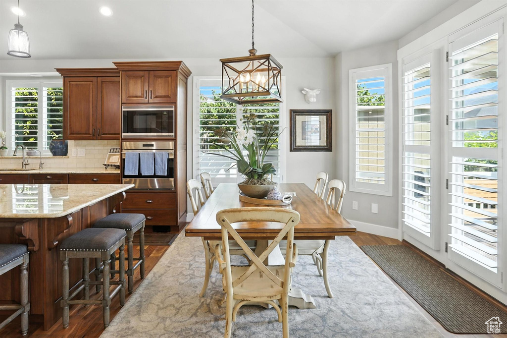 Dining space featuring healthy amount of natural light, dark wood finished floors, vaulted ceiling, and recessed lighting