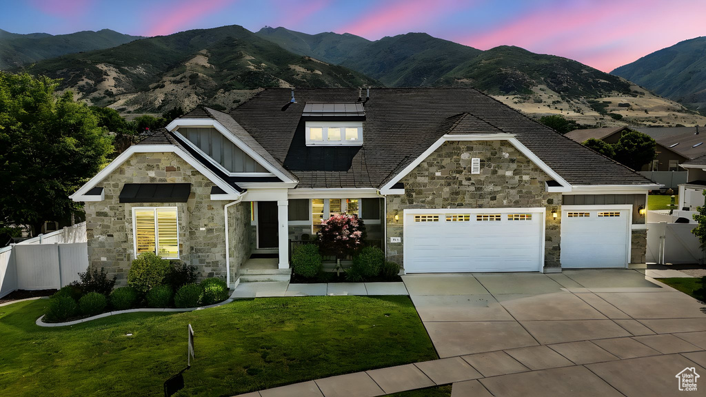 View of front of house featuring stone siding, a mountain view, board and batten siding, driveway, and an attached garage