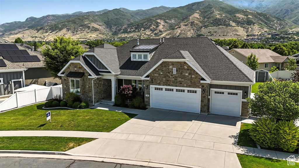 View of front facade with stone siding, driveway, a garage, and a mountain view