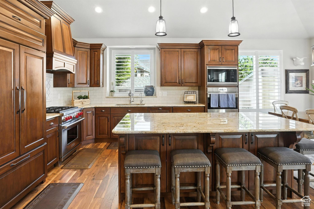 Kitchen featuring built in appliances, hardwood / wood-style flooring, healthy amount of natural light, decorative backsplash, and recessed lighting