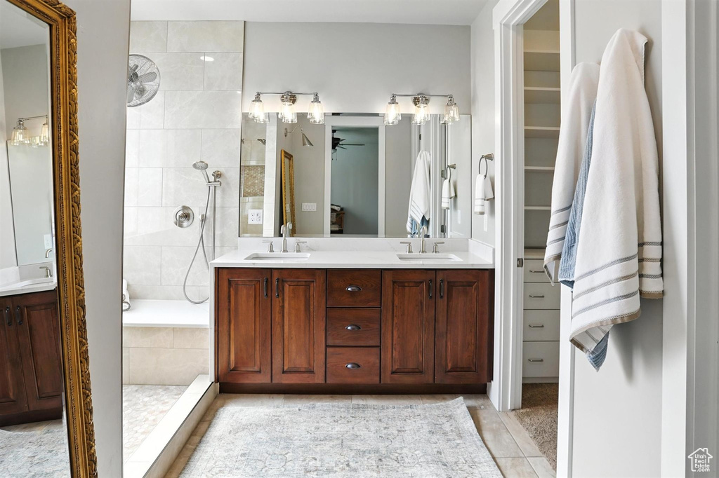 Bathroom featuring walk in shower, double vanity, tile patterned flooring, a ceiling fan, and a spacious closet