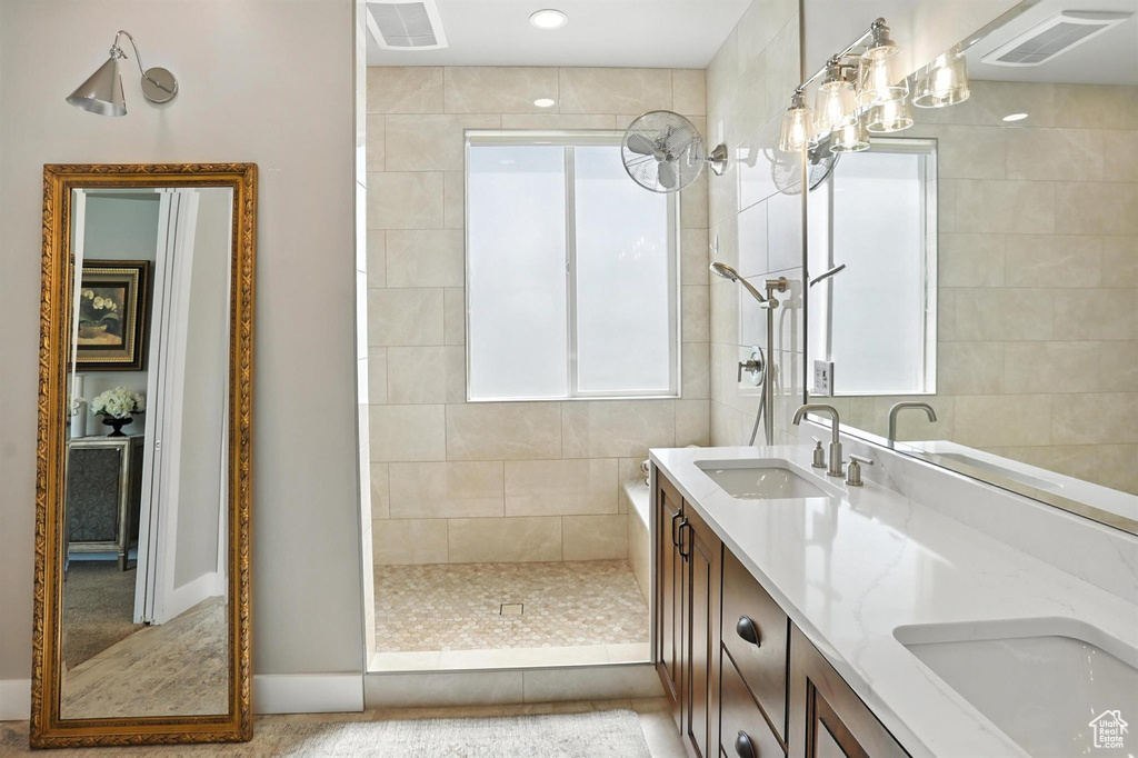 Bathroom featuring walk in shower, double vanity, and healthy amount of natural light