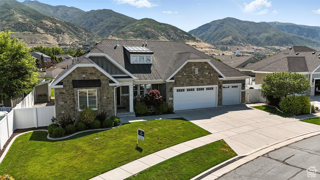 Craftsman inspired home featuring stone siding, concrete driveway, a mountain view, and an attached garage