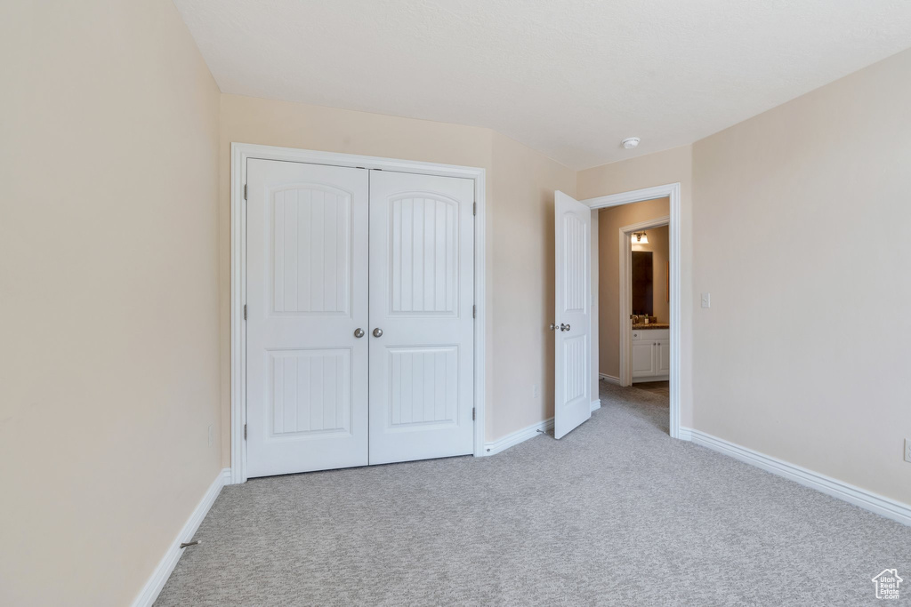 Unfurnished bedroom featuring light colored carpet and a closet