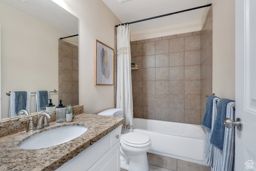 Full bath with vanity, tile patterned floors, and shower / bath combo with shower curtain