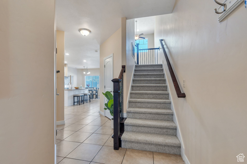 Staircase featuring a ceiling fan and tile patterned flooring