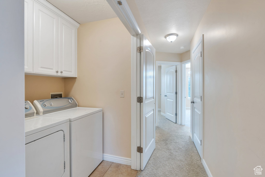 Laundry room featuring separate washer and dryer, cabinet space, and light carpet