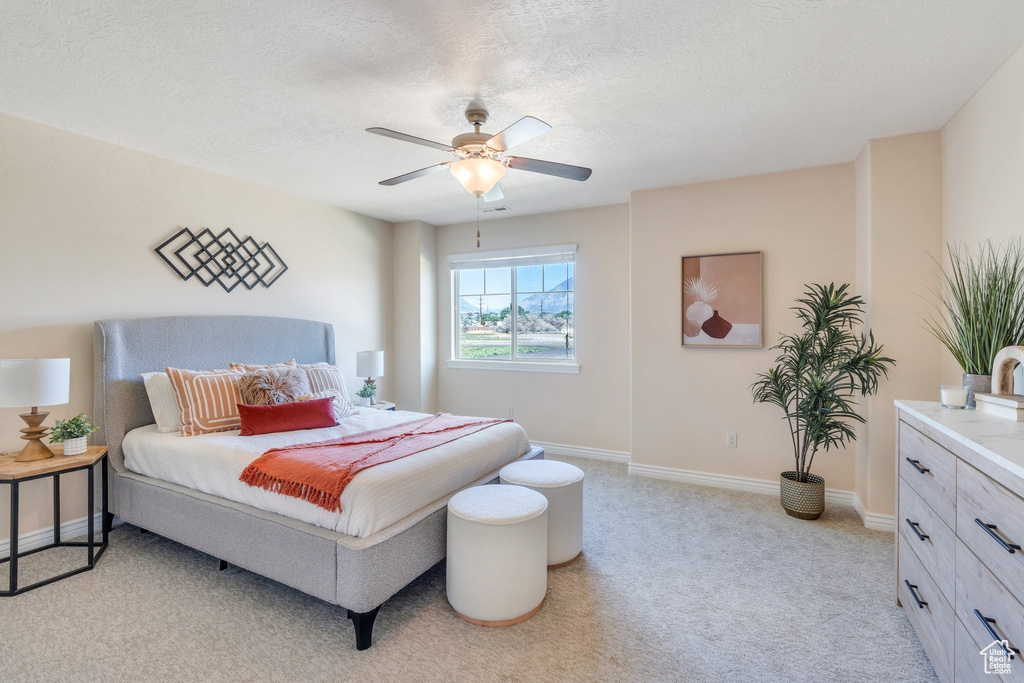 Bedroom with light colored carpet, a ceiling fan, and a textured ceiling