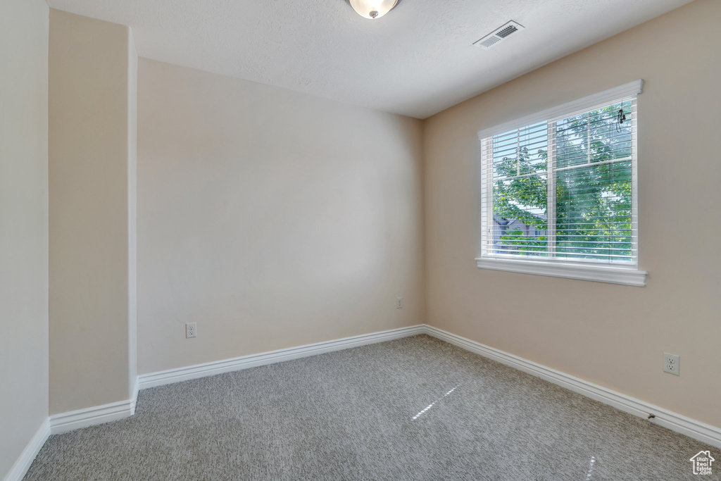 Carpeted spare room featuring baseboards