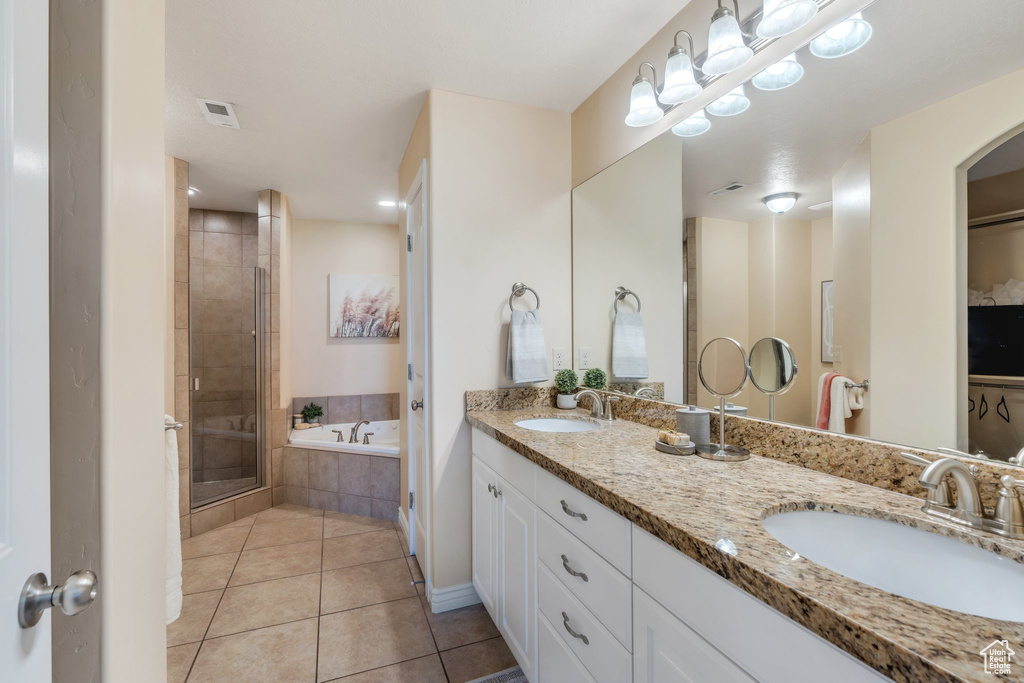 Bathroom with tile patterned floors, double vanity, a garden tub, and a stall shower
