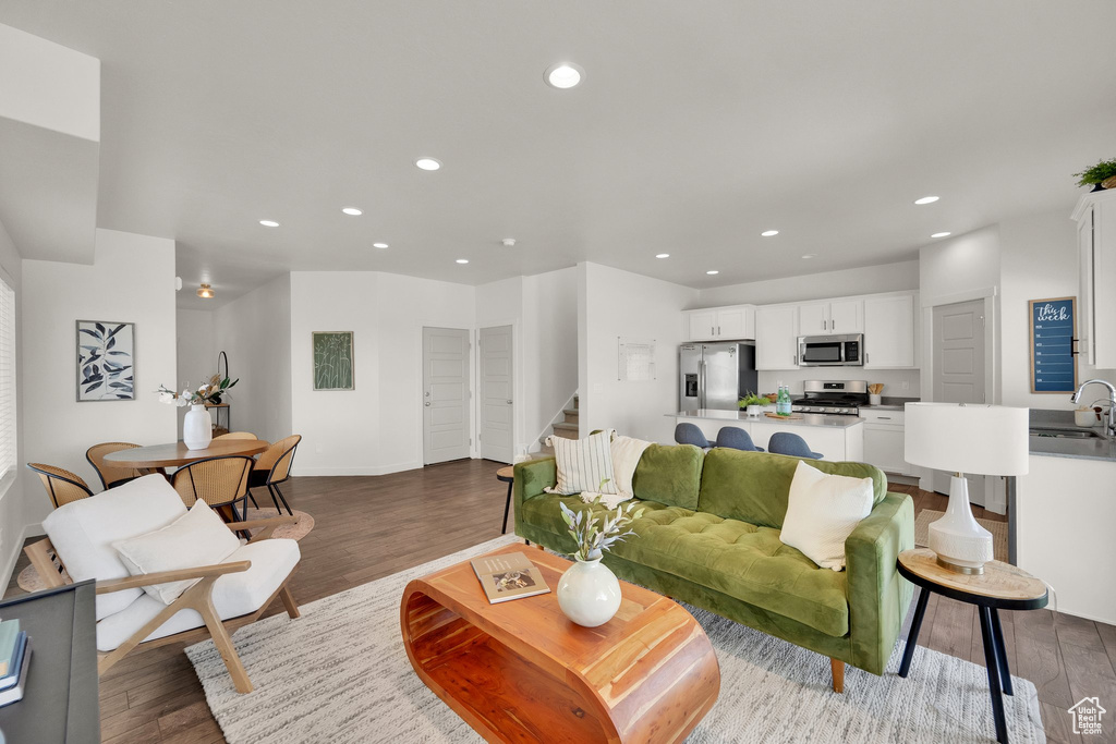 Living area featuring wood finished floors, recessed lighting, and stairs