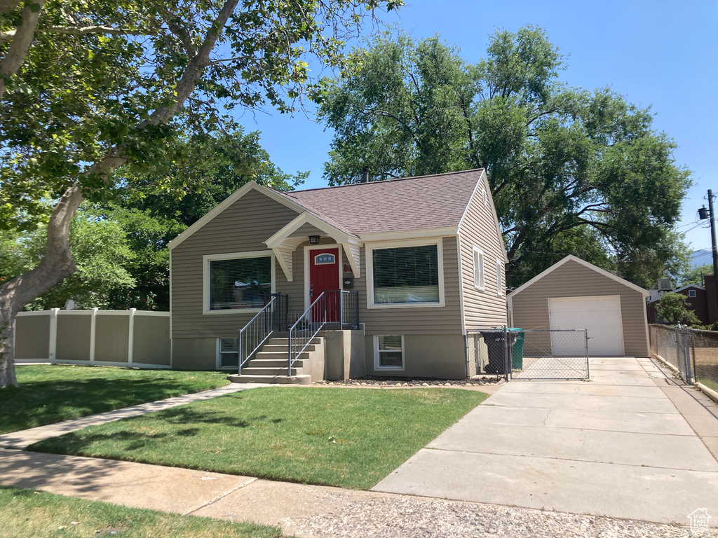 View of front facade featuring a garage, an outbuilding, driveway, and a shingled roof