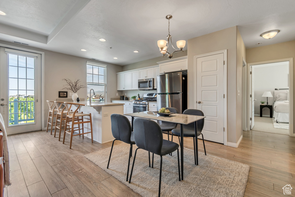 Dining room with light wood finished floors, a chandelier, and recessed lighting