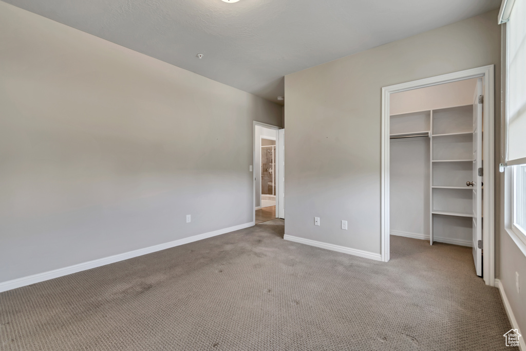 Unfurnished bedroom with carpet floors, a walk in closet, and a closet