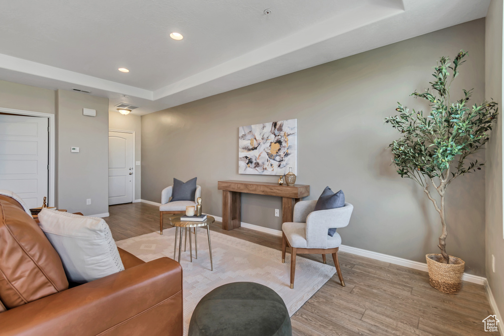 Living room with light wood-style flooring, recessed lighting, and a raised ceiling