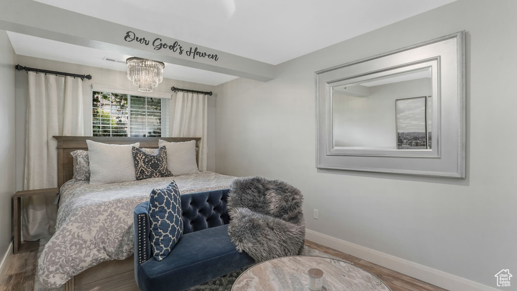 Bedroom with wood finished floors and a chandelier