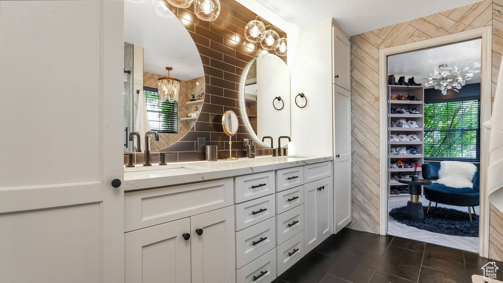 Bathroom featuring a chandelier, wood walls, double vanity, and tile patterned floors