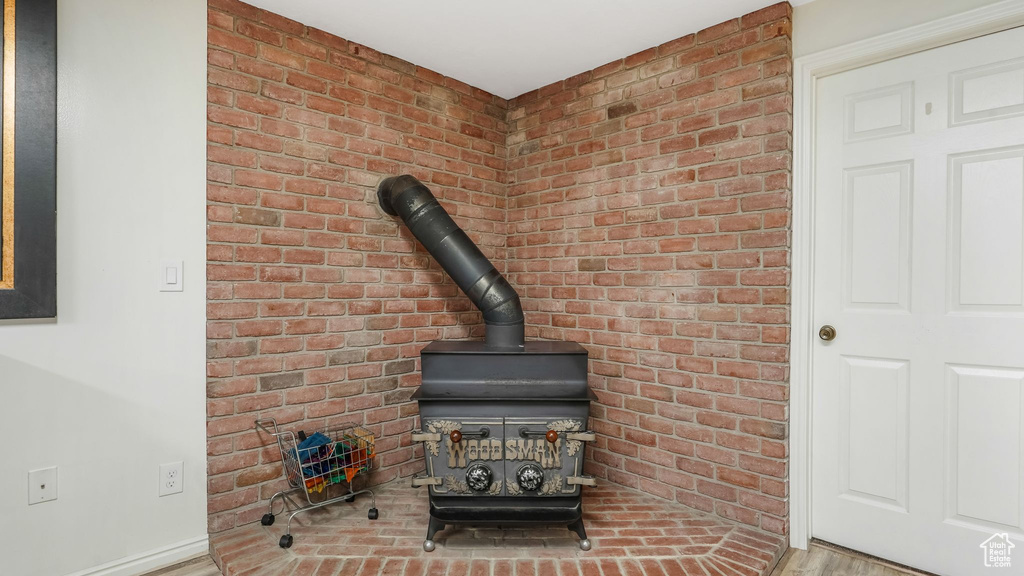 Detailed view of a wood stove, wood finished floors, and brick wall