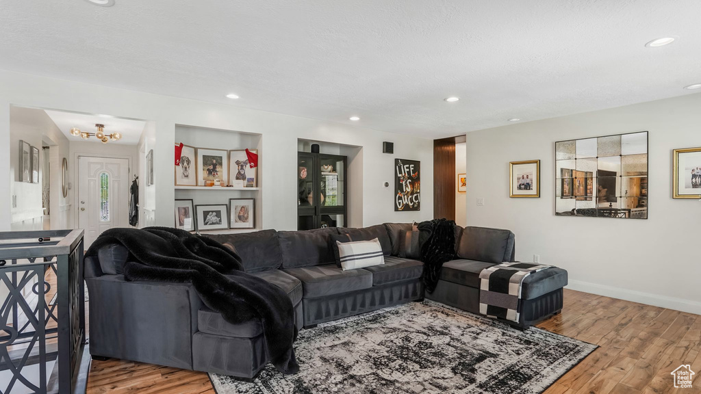 Living area with wood finished floors, a chandelier, and recessed lighting