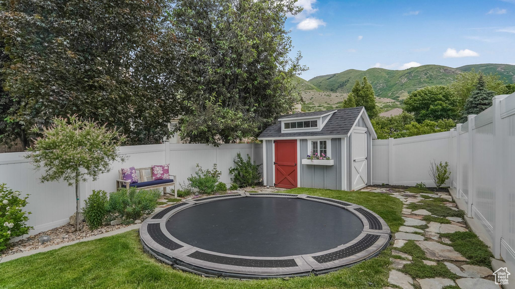 Fenced backyard with a trampoline, a shed, and a mountain view