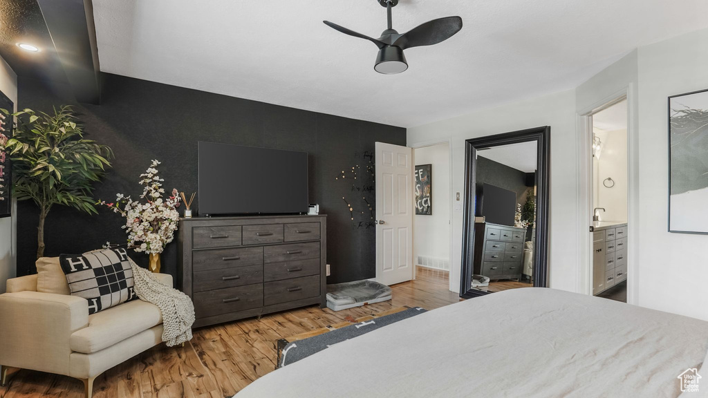 Bedroom featuring an accent wall, wood finished floors, and ensuite bathroom