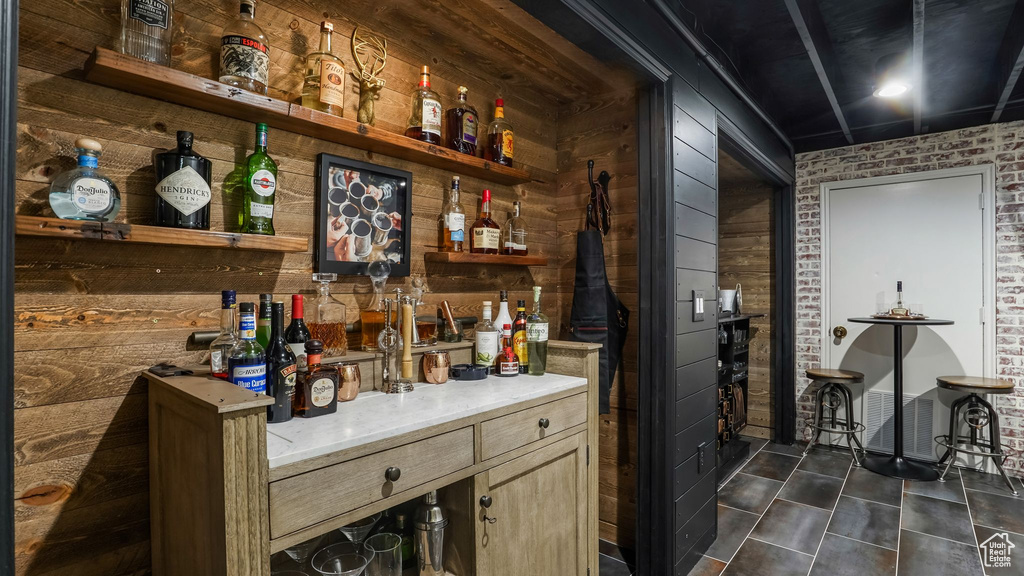 Indoor dry bar with wood walls and dark tile patterned flooring