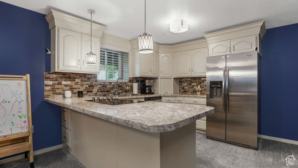 Kitchen featuring stainless steel appliances, a peninsula, decorative backsplash, and light carpet