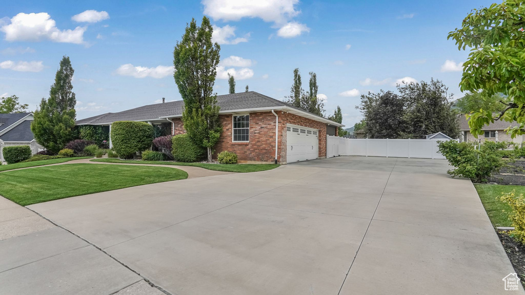 Single story home featuring brick siding, an attached garage, and driveway
