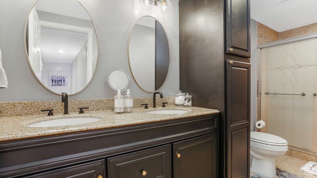 Full bath with double vanity, tile patterned floors, and a shower stall