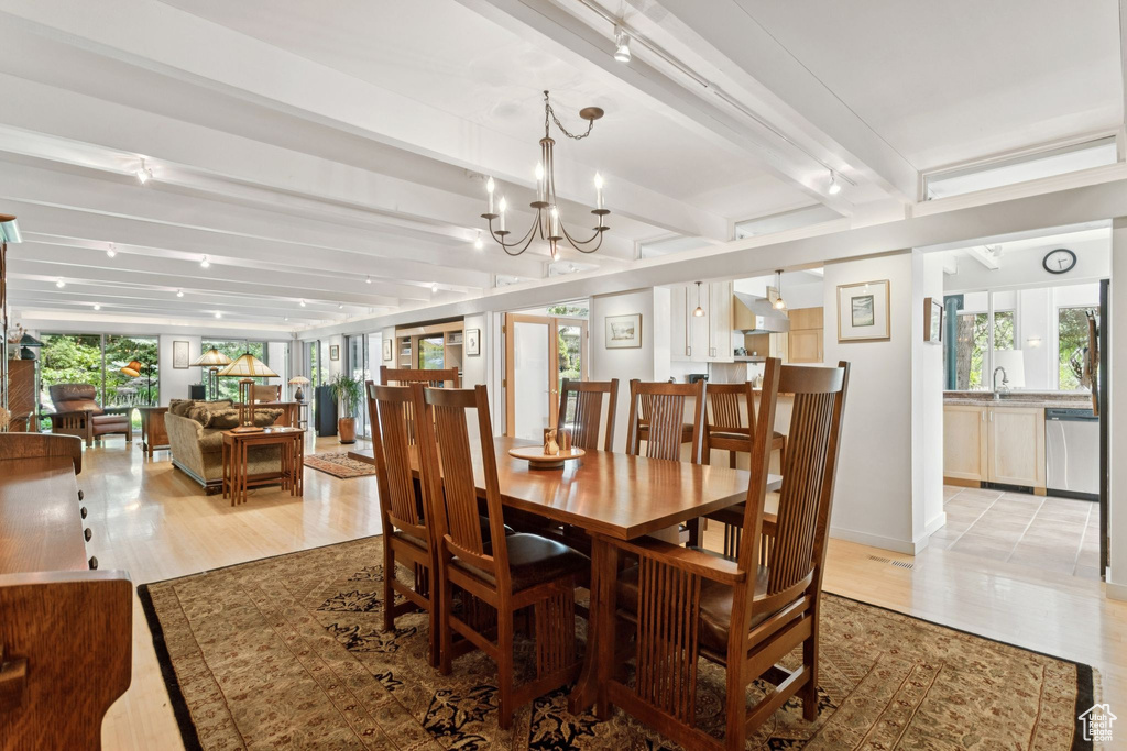 Dining area featuring beam ceiling, a chandelier, and light wood-style floors