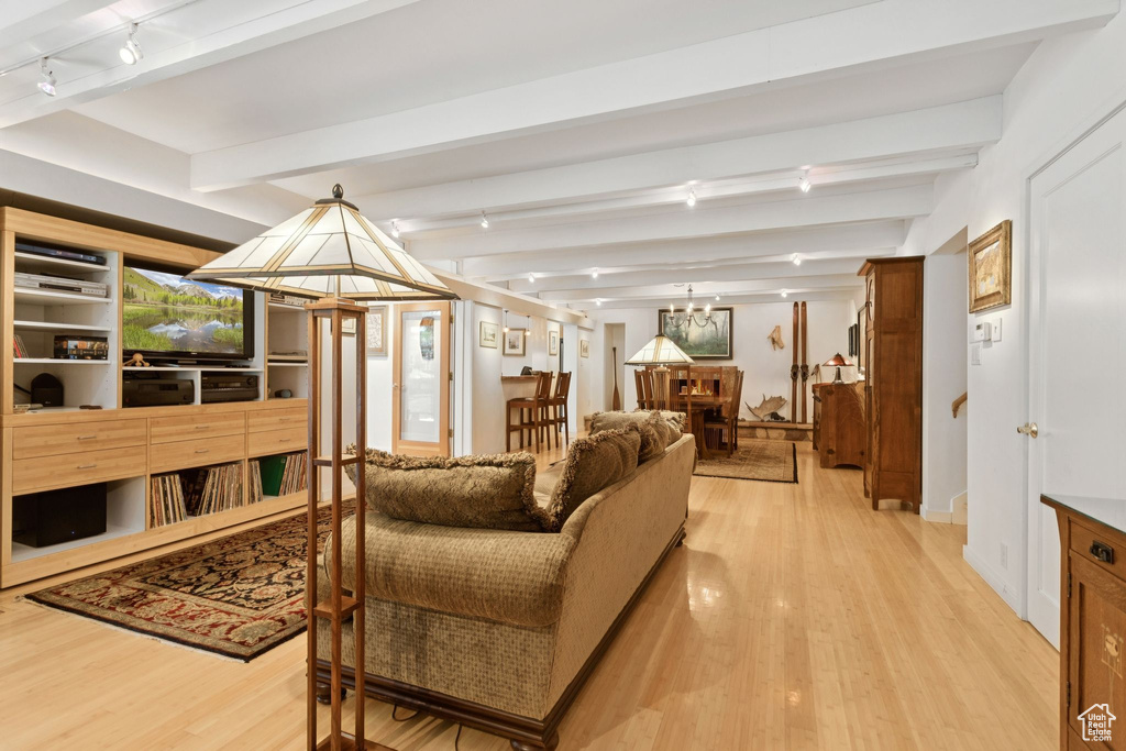 Living area with light wood-style flooring, beam ceiling, and track lighting