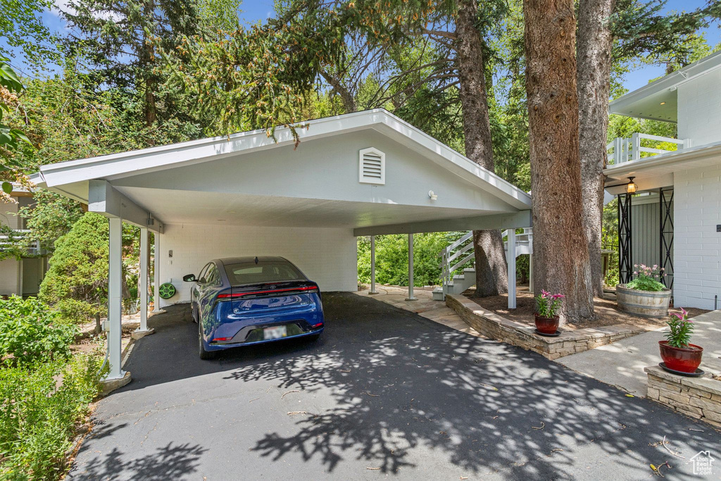 View of car parking featuring driveway, stairway, and an attached carport