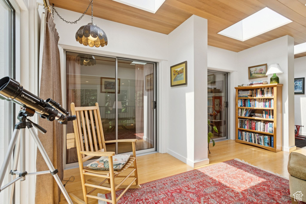 Living area with a skylight, wood finished floors, and wood ceiling