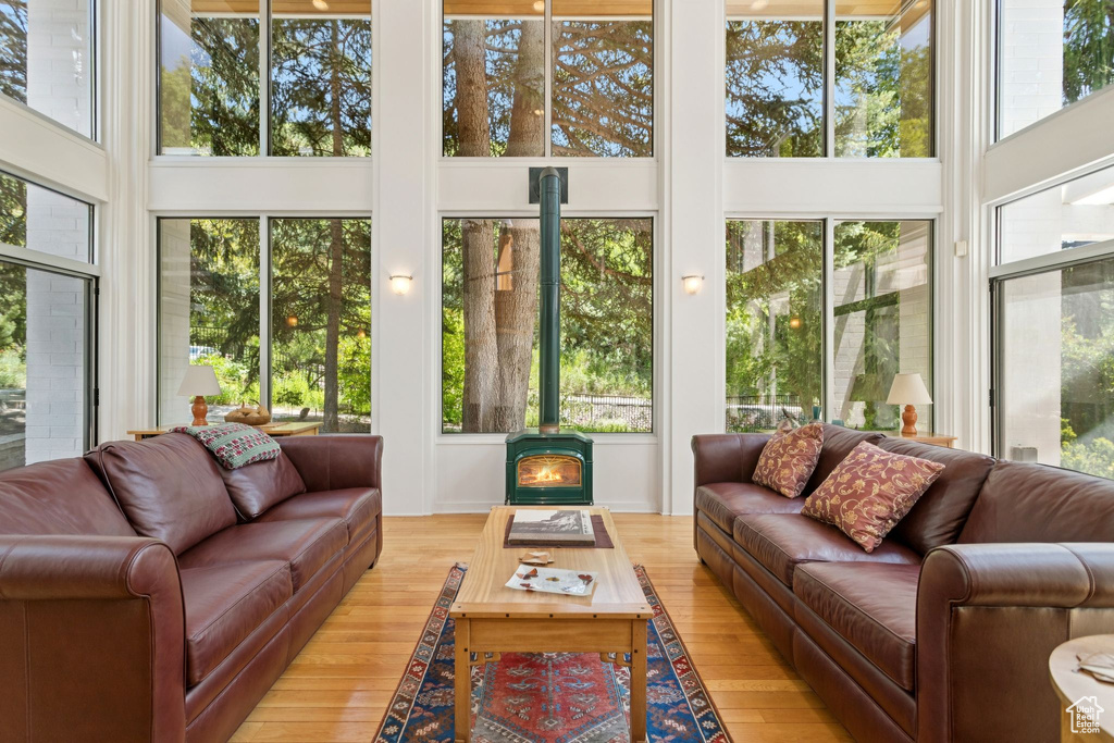 Sunroom featuring a high ceiling, wood finished floors, and a wood stove