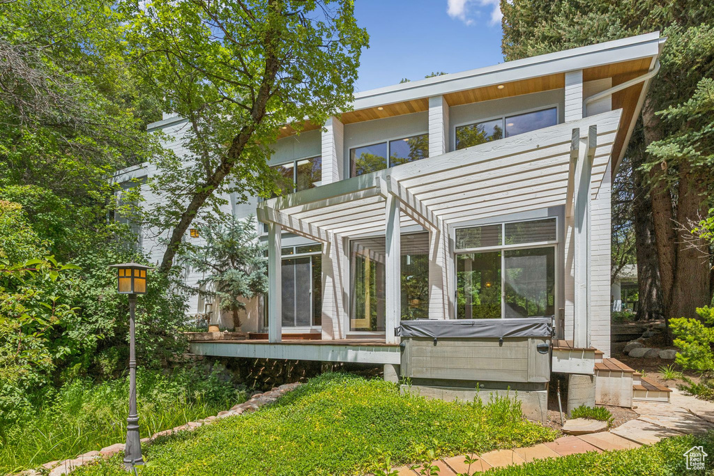 Back of house featuring a hot tub and a pergola
