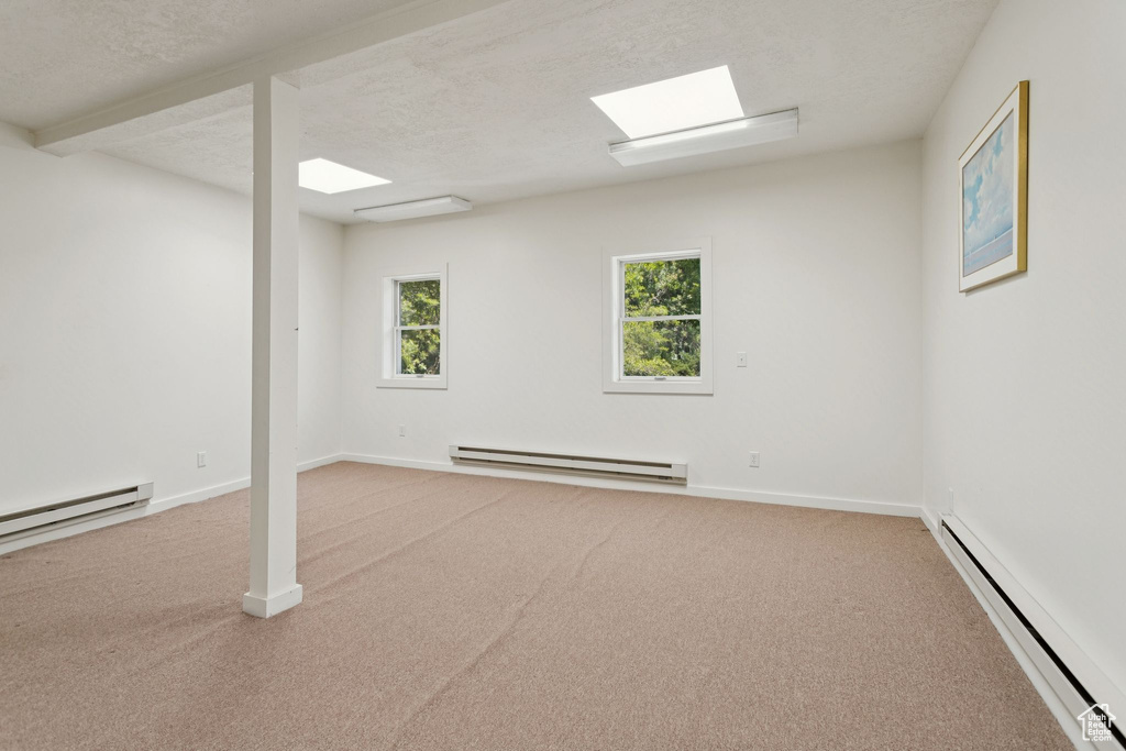 Below grade area with a baseboard radiator, carpet, and a textured ceiling