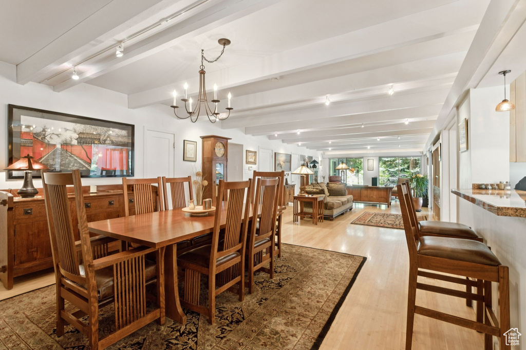 Dining area with wood finished floors, beam ceiling, and a chandelier