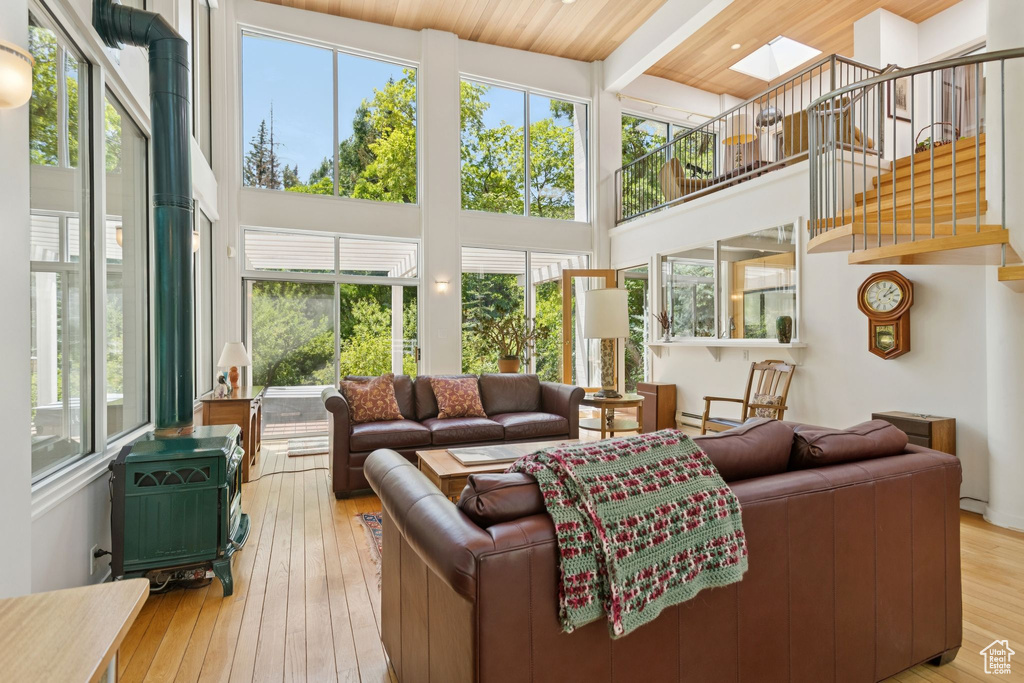 Living area featuring a wood stove, hardwood / wood-style flooring, beamed ceiling, a towering ceiling, and stairway