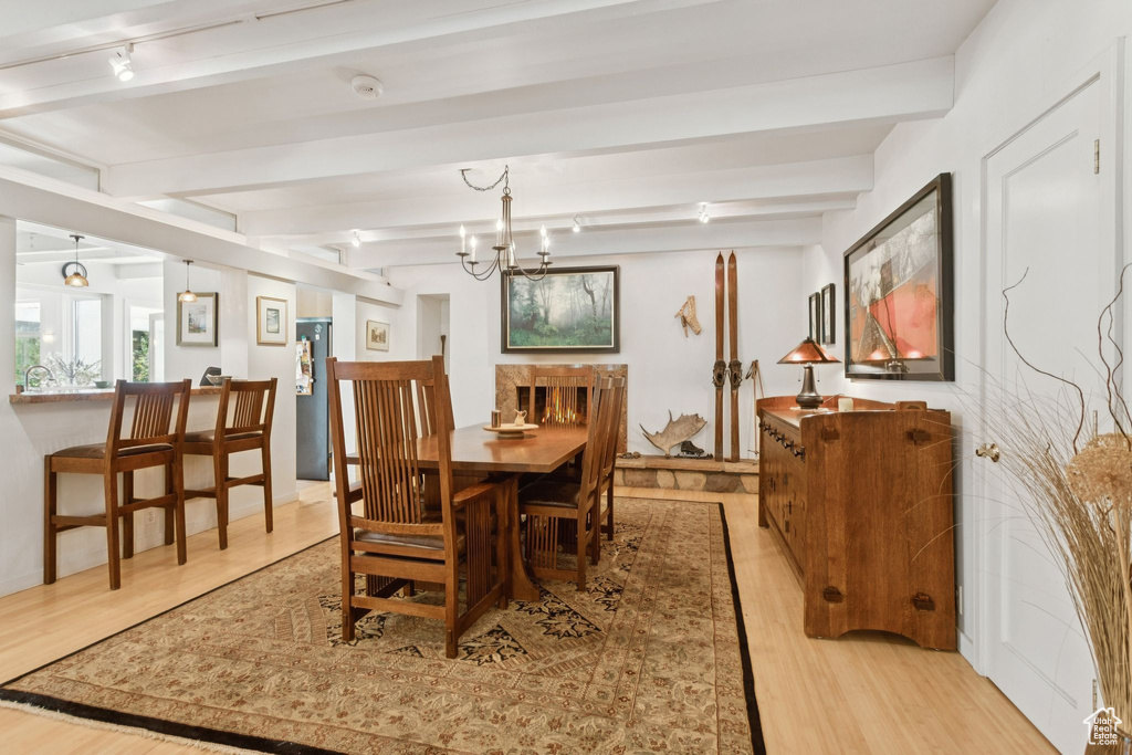 Dining space with light wood-type flooring, beamed ceiling, a chandelier, track lighting, and water heater