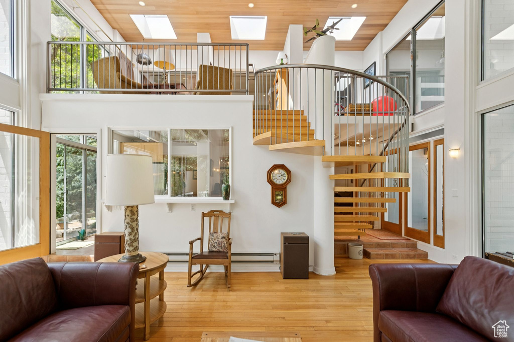 Living room featuring a skylight, wood-type flooring, a high ceiling, wood ceiling, and stairs