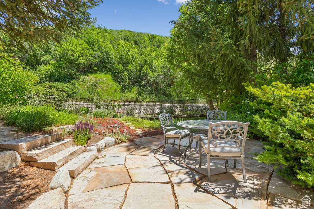 View of patio with outdoor dining space and a view of trees