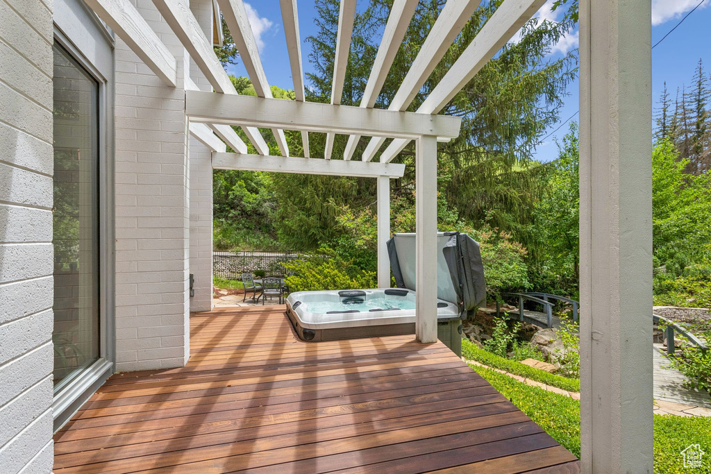 Deck featuring a covered hot tub and a pergola