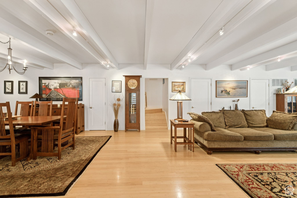 Living area with beam ceiling, light wood-type flooring, and a chandelier