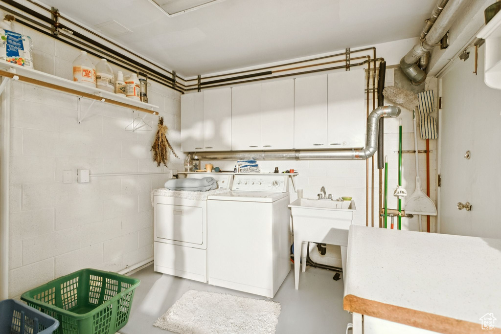 Laundry room with washer and clothes dryer, concrete block wall, and cabinet space