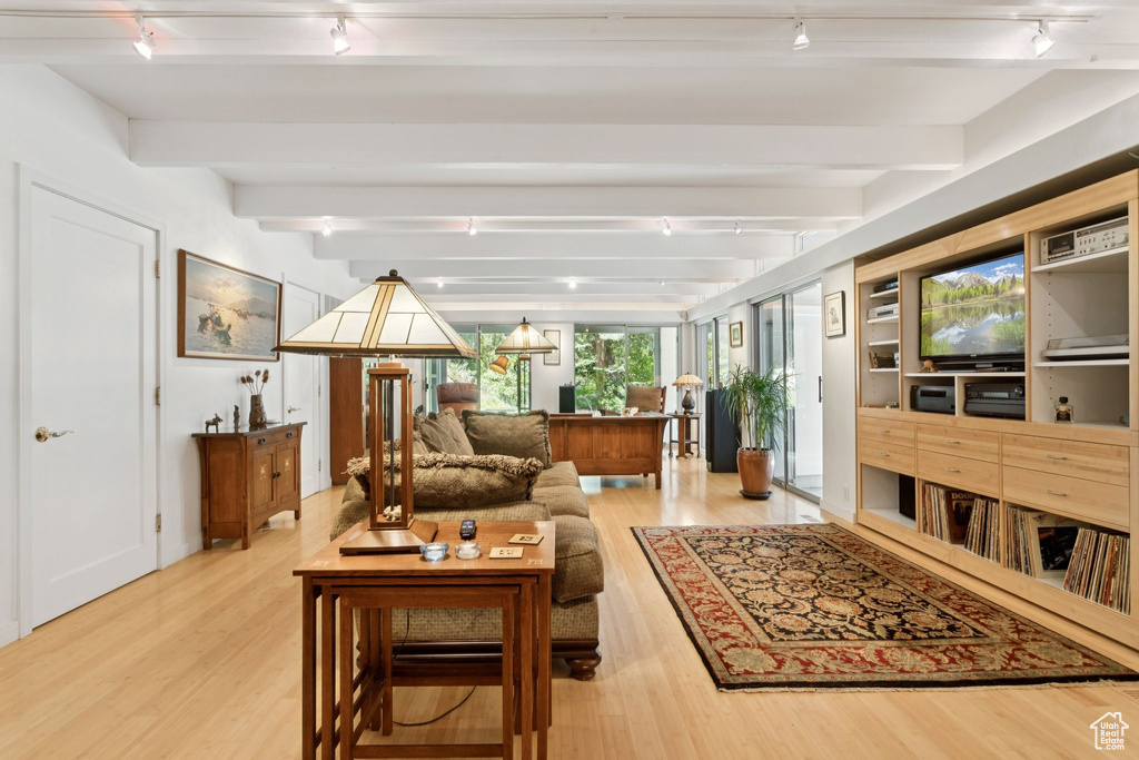 Living area featuring rail lighting, wood finished floors, and beam ceiling