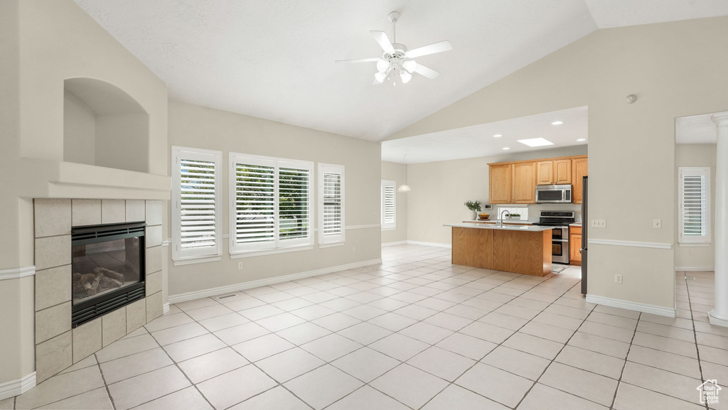 Living area with a ceiling fan, vaulted ceiling, a fireplace, light tile patterned flooring, and recessed lighting