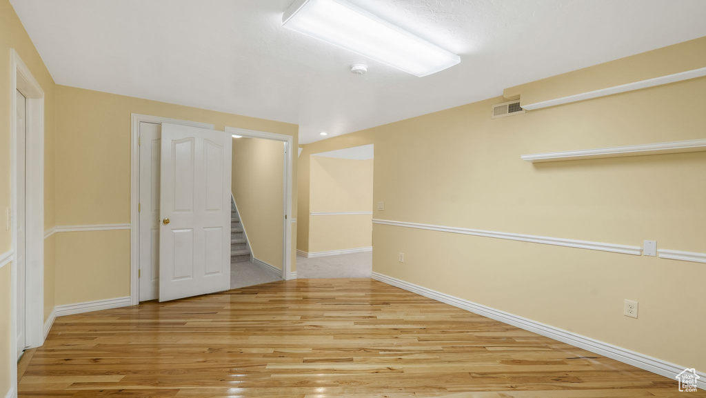 Empty room with wood finished floors, a smoke detector, and stairway