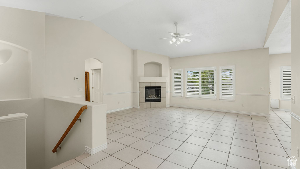 Unfurnished living room with vaulted ceiling, a ceiling fan, light tile patterned flooring, and a tile fireplace