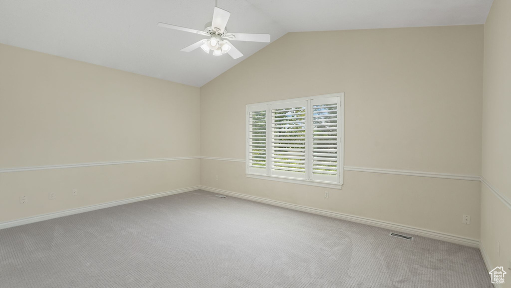 Carpeted spare room with ceiling fan and lofted ceiling